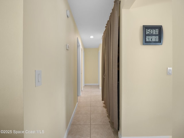 hall featuring baseboards, recessed lighting, and light tile patterned floors