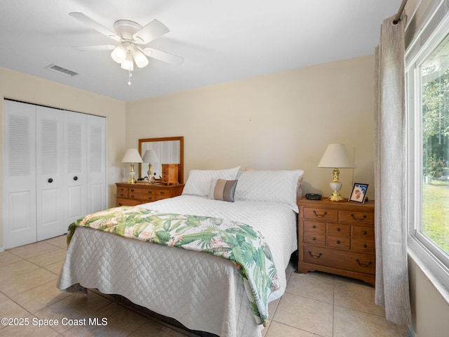 bedroom featuring light tile patterned flooring, visible vents, a ceiling fan, and a closet