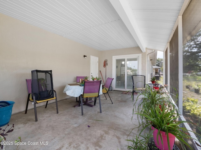 sunroom / solarium with concrete flooring and beamed ceiling