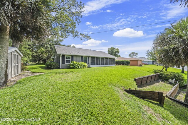 101 Joy Haven Dr, Sebastian, FL 32958 - rear view of property with an outdoor structure, a storage unit, roof with shingles, a yard, and a sunroom