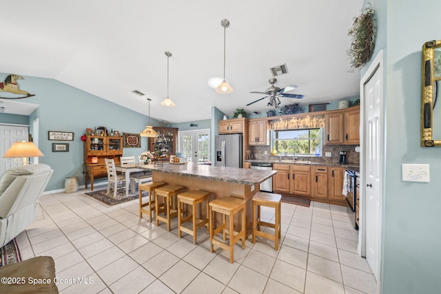 101 Joy Haven Dr, Sebastian, FL 32958 - kitchen with tasteful backsplash, stainless steel appliances, vaulted ceiling, a sink, and light tile patterned flooring