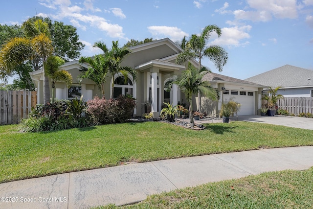 view of front of property featuring driveway, fence, a garage, a front yard, and stucco siding