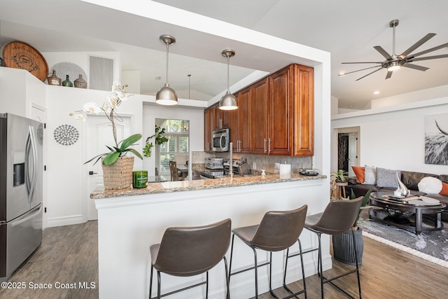 kitchen featuring a ceiling fan, tasteful backsplash, wood finished floors, a breakfast bar, and appliances with stainless steel finishes