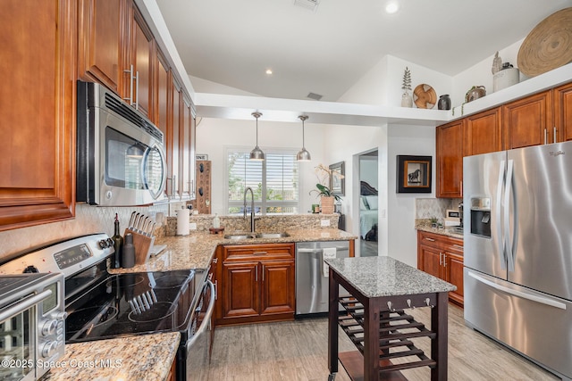 kitchen with appliances with stainless steel finishes, tasteful backsplash, a sink, and light wood-style flooring
