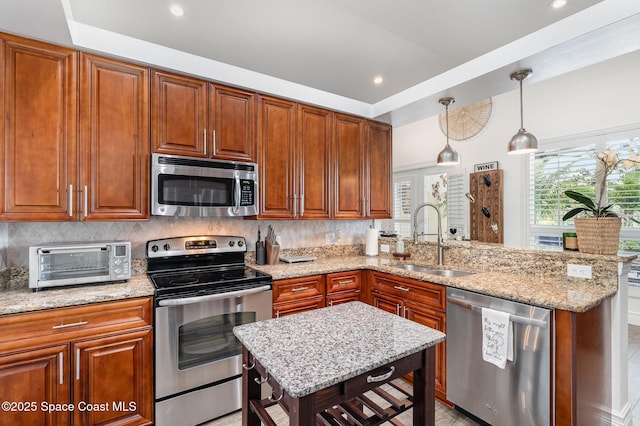 kitchen with a toaster, light stone counters, a sink, a peninsula, and appliances with stainless steel finishes