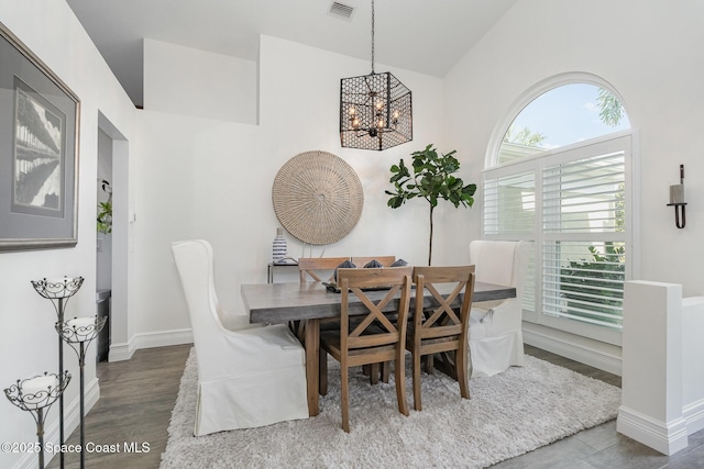 dining room with vaulted ceiling, wood finished floors, an inviting chandelier, baseboards, and visible vents