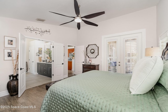 bedroom with vaulted ceiling, wood finished floors, visible vents, baseboards, and access to outside