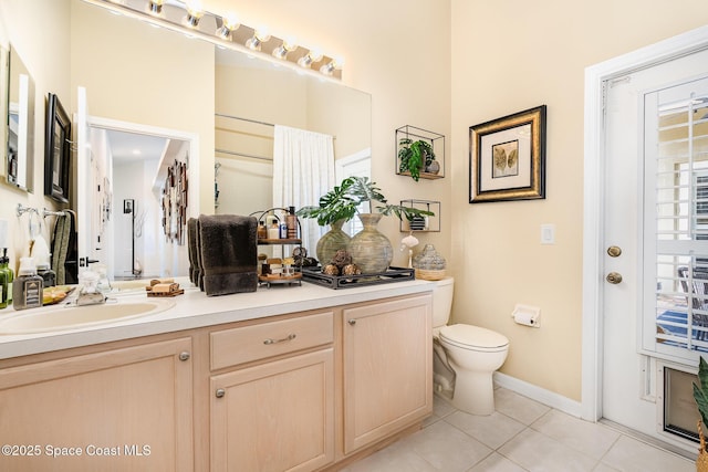 bathroom featuring toilet, vanity, tile patterned floors, and baseboards