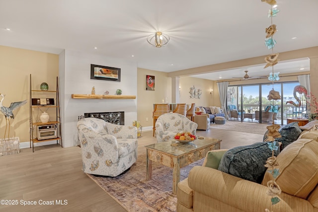 living area featuring baseboards, light wood-type flooring, a ceiling fan, and recessed lighting
