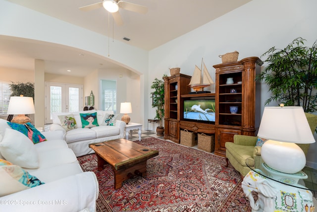 living room featuring a ceiling fan, arched walkways, and visible vents