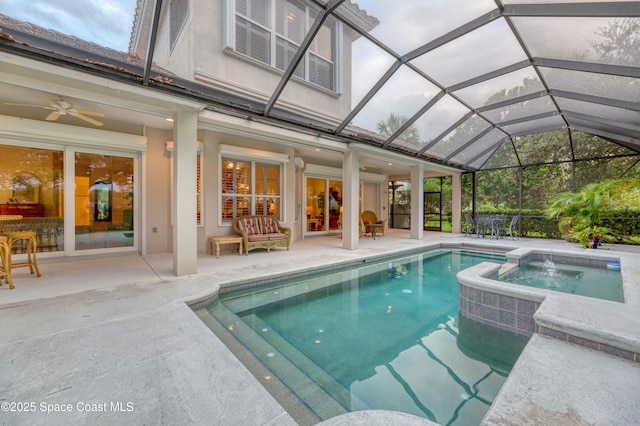 view of swimming pool featuring a ceiling fan, a patio, glass enclosure, and a pool with connected hot tub