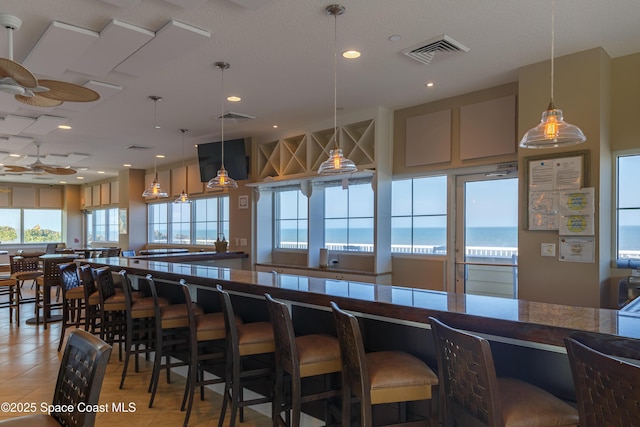 kitchen featuring recessed lighting, decorative light fixtures, a kitchen bar, visible vents, and light tile patterned flooring