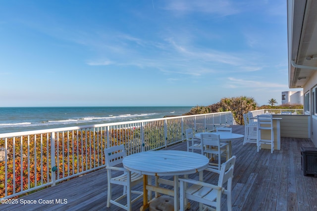 deck featuring a beach view, a water view, and outdoor dining area
