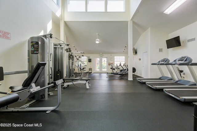 exercise room with visible vents and high vaulted ceiling