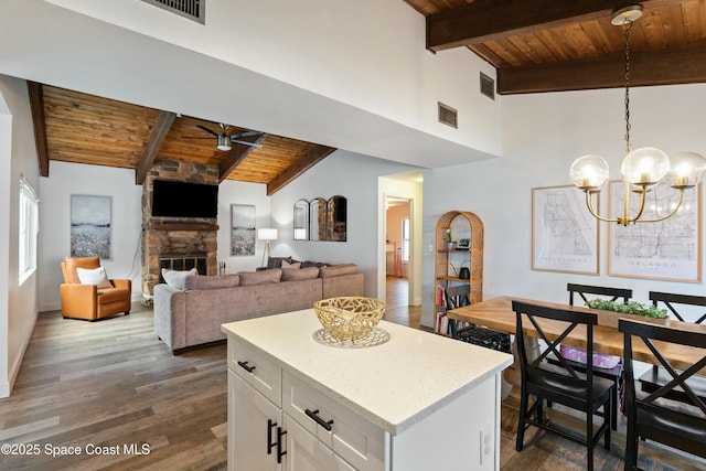 kitchen with visible vents, beamed ceiling, ceiling fan with notable chandelier, wood ceiling, and a fireplace