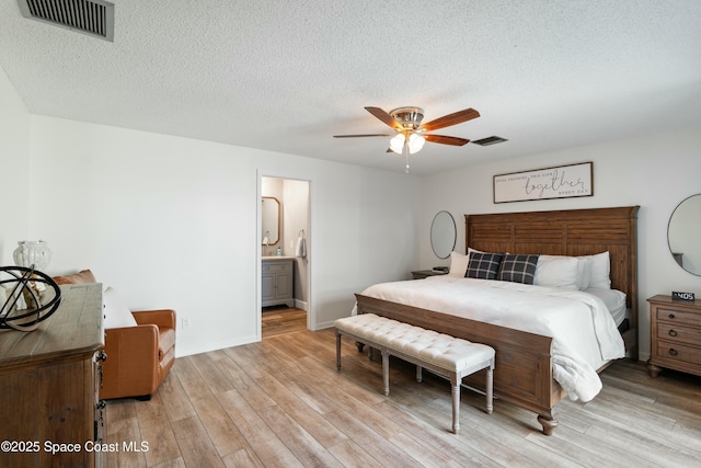 bedroom with light wood-style floors, visible vents, and a textured ceiling