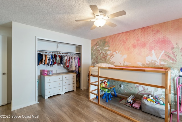 bedroom featuring baseboards, wood finished floors, a textured ceiling, and a closet