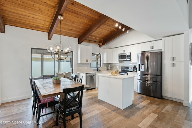 kitchen featuring plenty of natural light, light countertops, lofted ceiling with beams, a chandelier, and appliances with stainless steel finishes