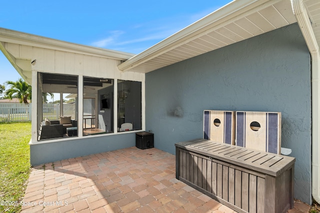 view of patio / terrace featuring fence and a sunroom