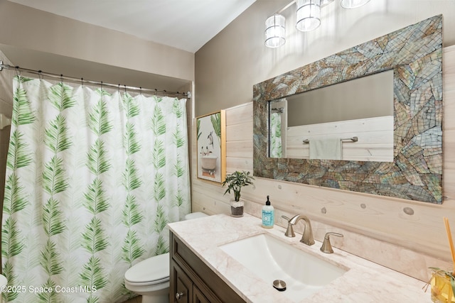 bathroom featuring toilet, vanity, and curtained shower