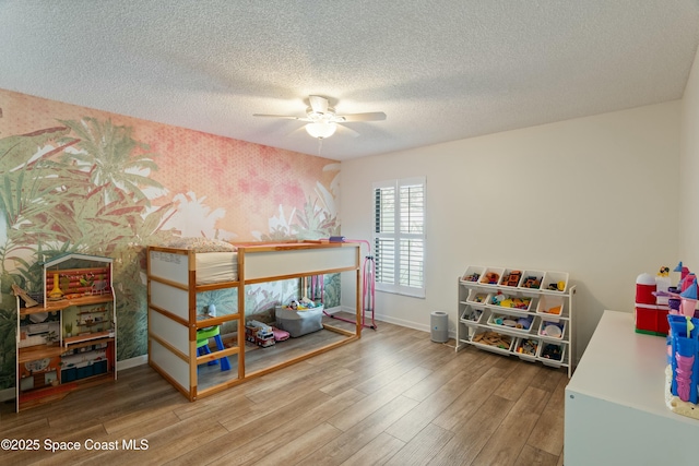 bedroom featuring a textured ceiling, baseboards, wallpapered walls, wood finished floors, and ceiling fan