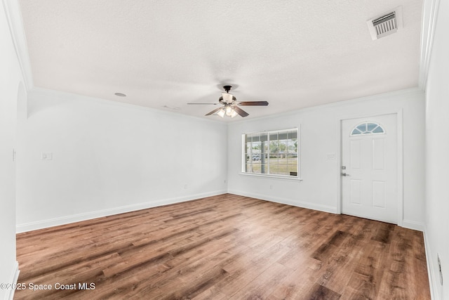 interior space with wood finished floors, visible vents, ceiling fan, and ornamental molding