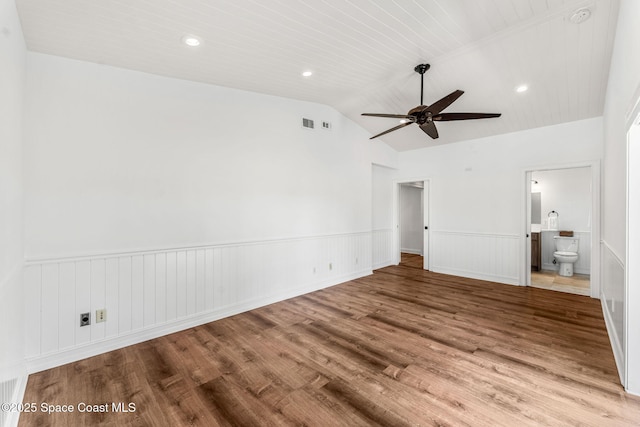 unfurnished bedroom featuring lofted ceiling, a wainscoted wall, recessed lighting, wood finished floors, and ensuite bath