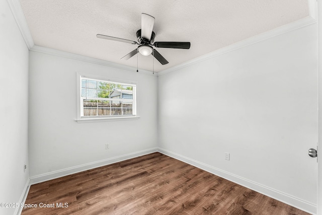 spare room with wood finished floors, crown molding, a ceiling fan, and baseboards