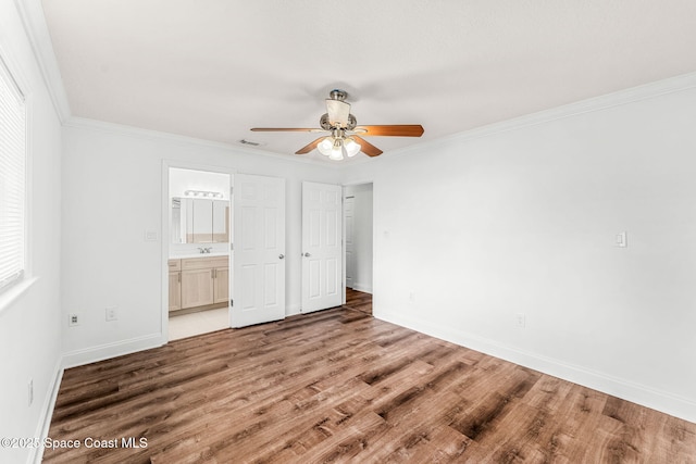 unfurnished bedroom featuring wood finished floors, crown molding, visible vents, and baseboards