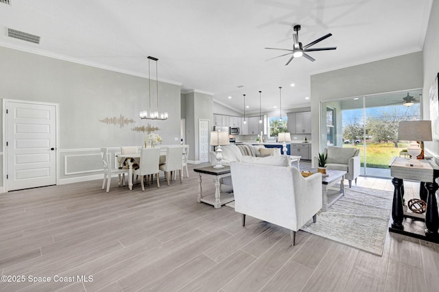 living room with light wood-type flooring, visible vents, ceiling fan with notable chandelier, and crown molding