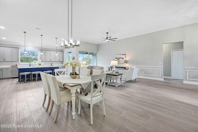 dining space featuring a healthy amount of sunlight, ceiling fan with notable chandelier, and light wood finished floors