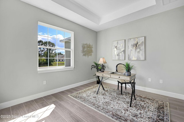 office with baseboards, wood finished floors, and a raised ceiling