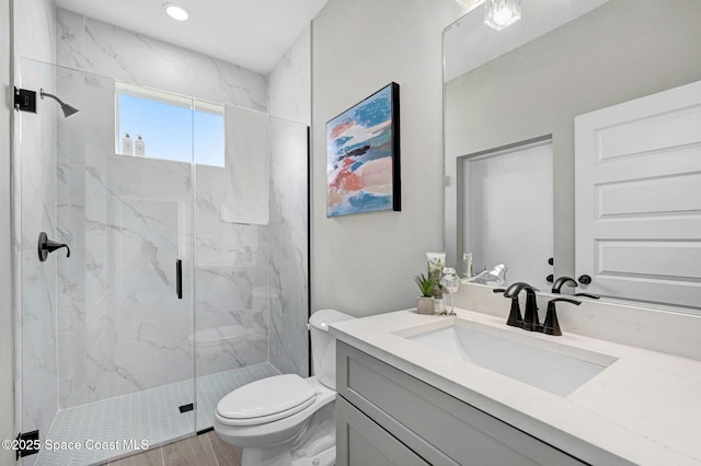 bathroom featuring toilet, a marble finish shower, wood finished floors, and vanity