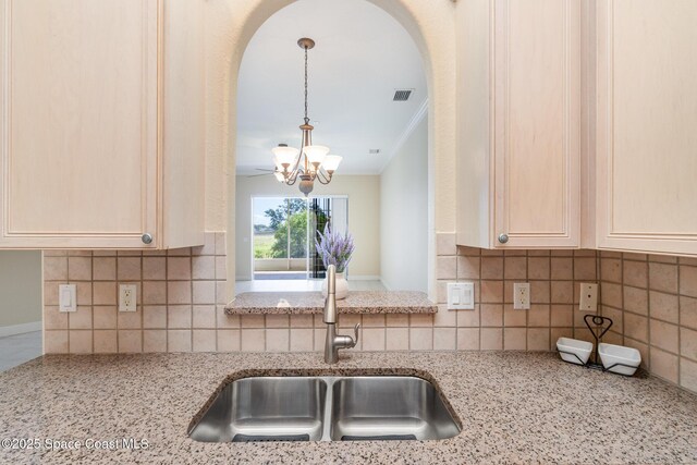 kitchen featuring an inviting chandelier, a sink, arched walkways, and tasteful backsplash