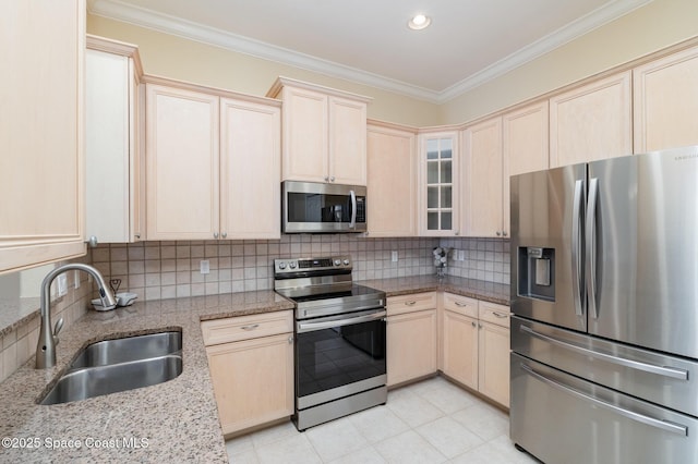 kitchen featuring light brown cabinetry, crown molding, appliances with stainless steel finishes, a sink, and backsplash
