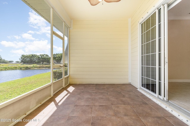 unfurnished sunroom with a ceiling fan and a water view