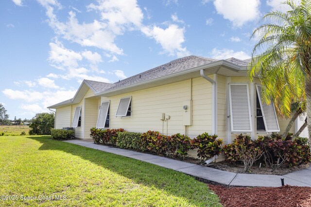 view of property exterior featuring a lawn and roof with shingles
