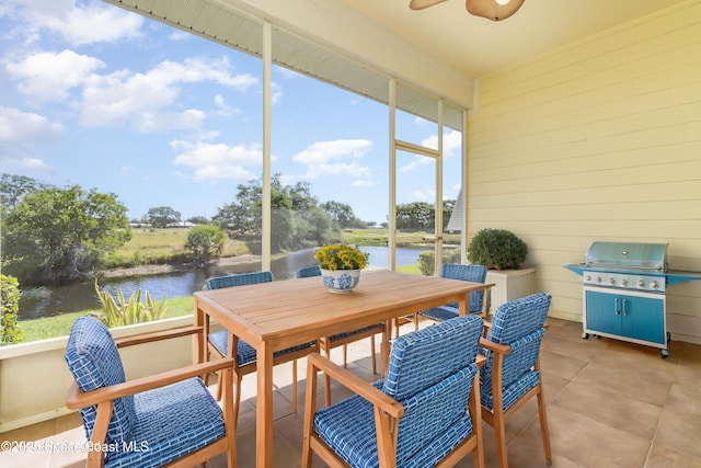 sunroom featuring a water view, a ceiling fan, and outdoor dining area