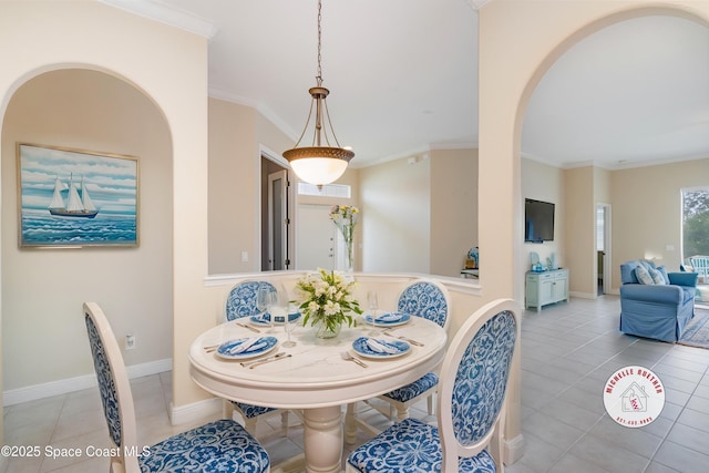 tiled dining space with crown molding, arched walkways, and baseboards
