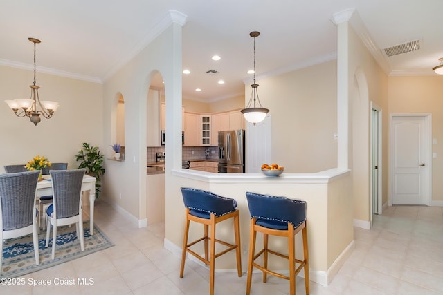 kitchen with glass insert cabinets, decorative backsplash, visible vents, arched walkways, and stainless steel fridge