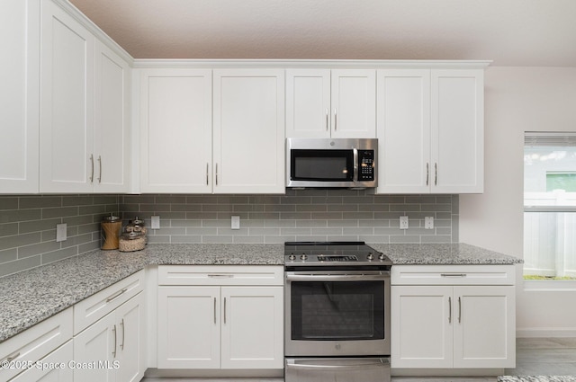 kitchen featuring white cabinets, decorative backsplash, and stainless steel appliances
