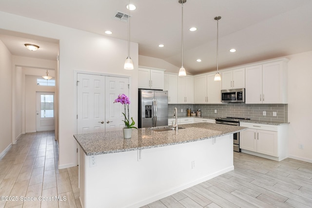 kitchen featuring a sink, white cabinets, wood finish floors, backsplash, and appliances with stainless steel finishes