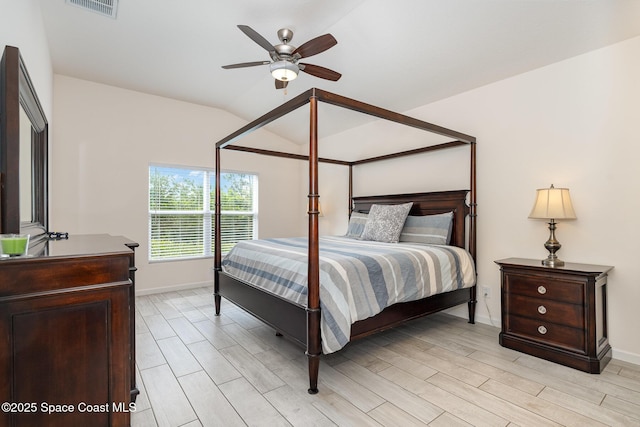 bedroom with light wood-style floors, visible vents, baseboards, and lofted ceiling