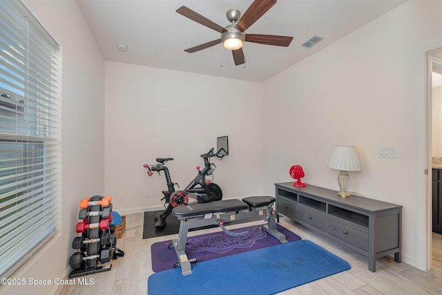 exercise room featuring a ceiling fan, baseboards, visible vents, and light wood-style floors