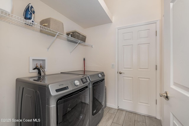 laundry room with baseboards, laundry area, washer and dryer, and light wood-type flooring