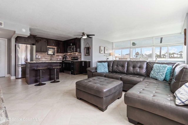 living area with ceiling fan and light tile patterned flooring