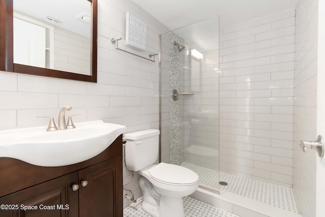 bathroom featuring visible vents, tile walls, a tile shower, vanity, and toilet