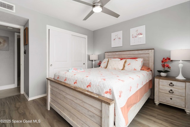 bedroom with a ceiling fan, baseboards, wood finished floors, visible vents, and a closet