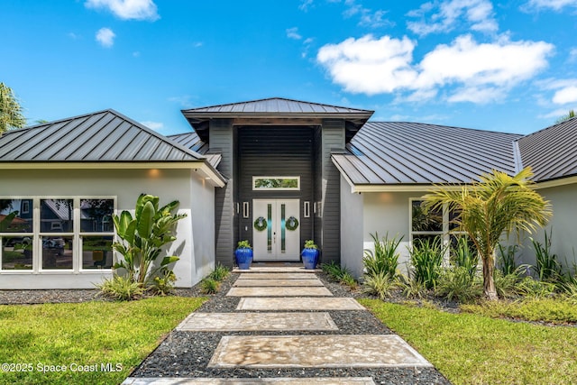 view of front of home with a standing seam roof, metal roof, stucco siding, a front lawn, and french doors