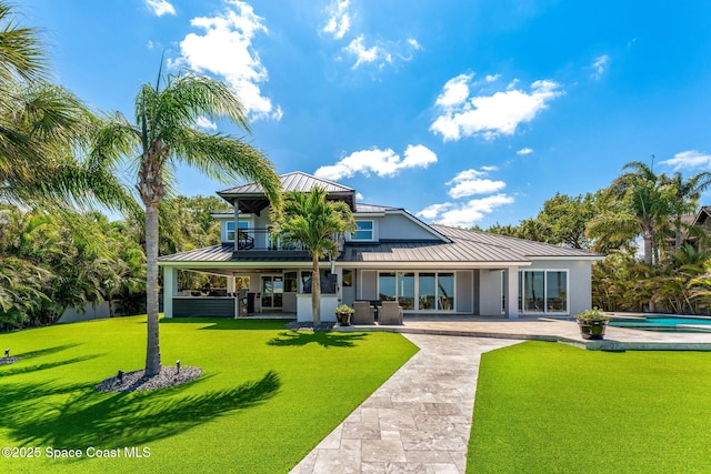 back of house with a standing seam roof, metal roof, a patio area, an outdoor pool, and a yard